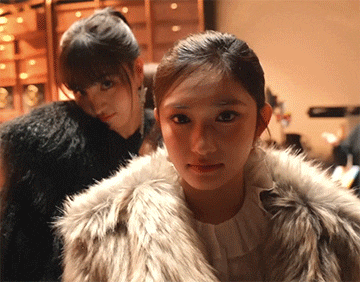 a woman in a fur coat stands next to another woman in a fur coat