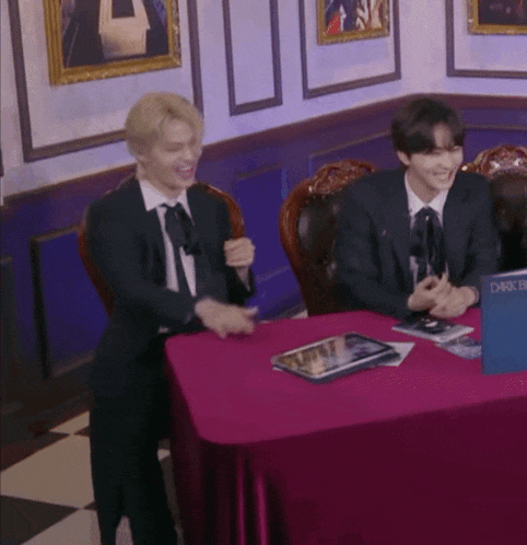 two men in suits are sitting at a table with a book that says dark de
