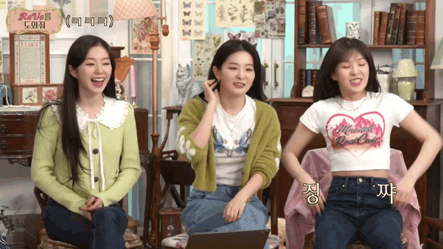 three women are sitting in front of a laptop and one of them has a shirt that says " magical red velvet "