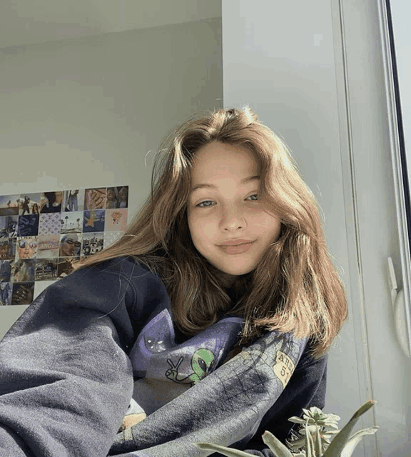 a girl wearing a sweatshirt with an alien on it poses for a photo