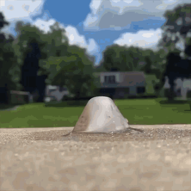 a cone shaped object is sitting on a concrete surface in front of a house
