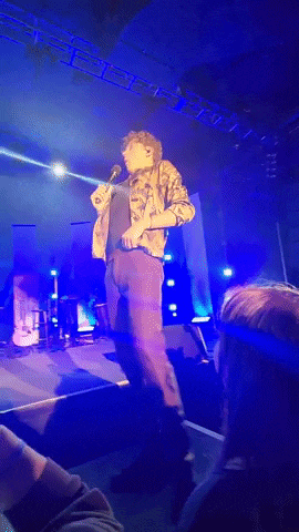 a man singing into a microphone on stage