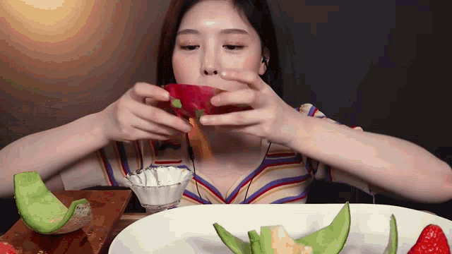 a woman is eating a slice of dragon fruit from a plate .