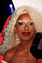 a woman with blonde hair and red lips is holding a camera