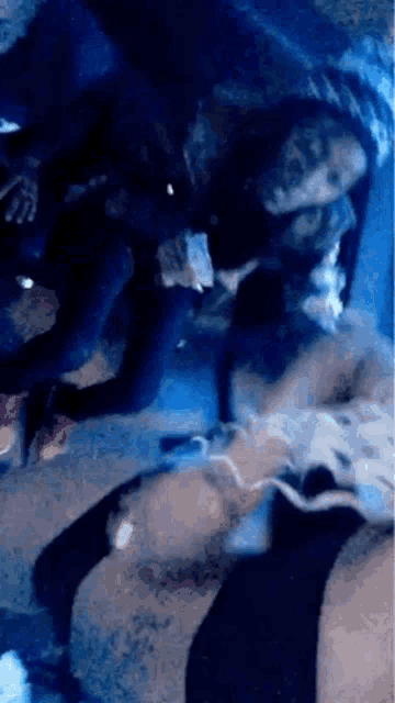 a blurry picture of a group of people in a dark room with a blue light behind them