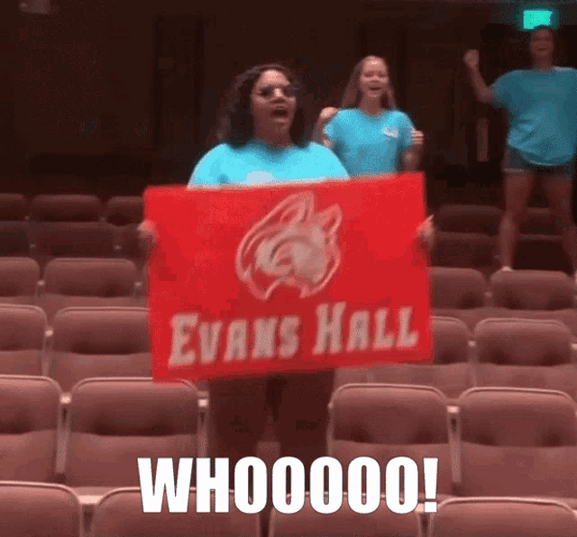 a woman holding a red sign that says evans hall whooooo