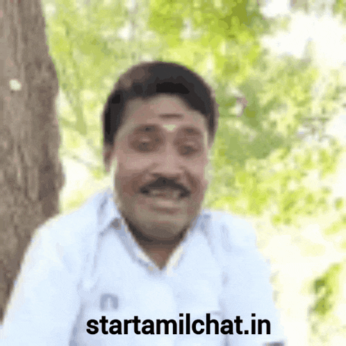 a man with a mustache is smiling in front of a tree and the words starttamilchat.in are visible .