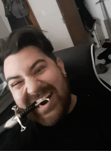 a man with a beard is holding a small sword in his mouth