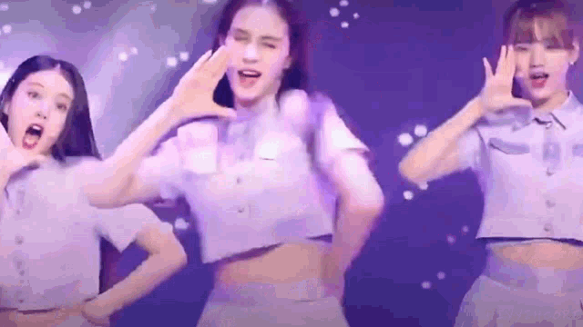a group of girls are dancing on a stage in purple outfits .