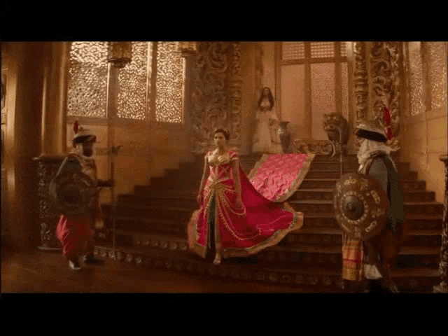 a woman in a long red dress is standing on stairs