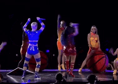 a group of people are dancing on a stage with a purple background .