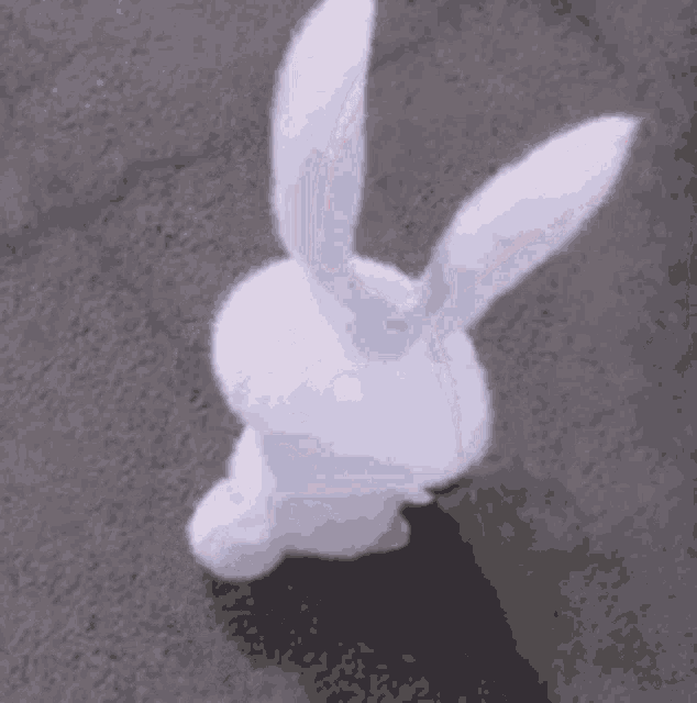 a white stuffed bunny rabbit with long ears is standing on the ground .