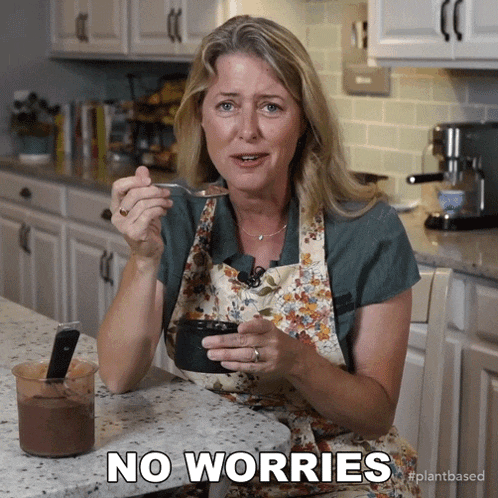 a woman in an apron is eating a spoonful of food with the words no worries below her