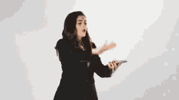 a woman in a suit is holding a cell phone and throwing money into the air .
