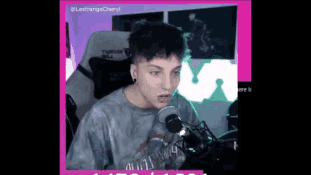 a man wearing a tie dye shirt is sitting in front of a microphone