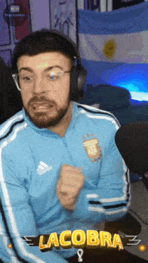 a man wearing headphones and a blue adidas jacket with the word la cobra on it