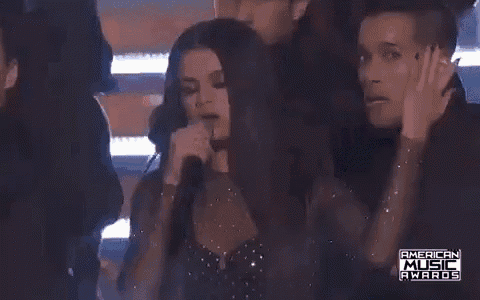 a woman is singing into a microphone at the american music awards