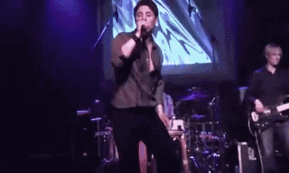 a man singing into a microphone on stage