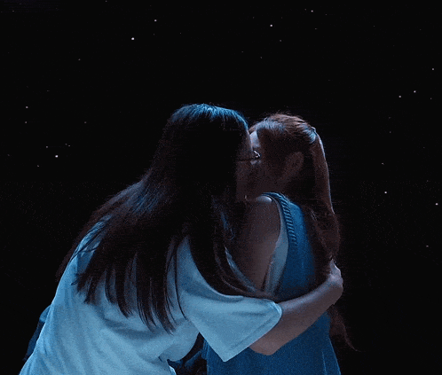 two women kissing in a dark room with stars in the background