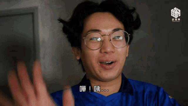 a man wearing glasses and a blue shirt has chinese writing on his shirt