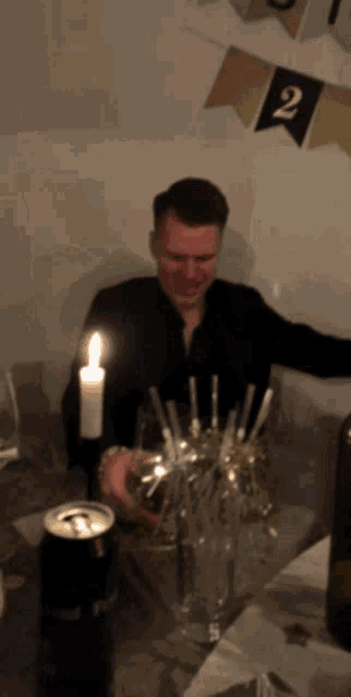 a man sitting at a table with a candle and a can of beer
