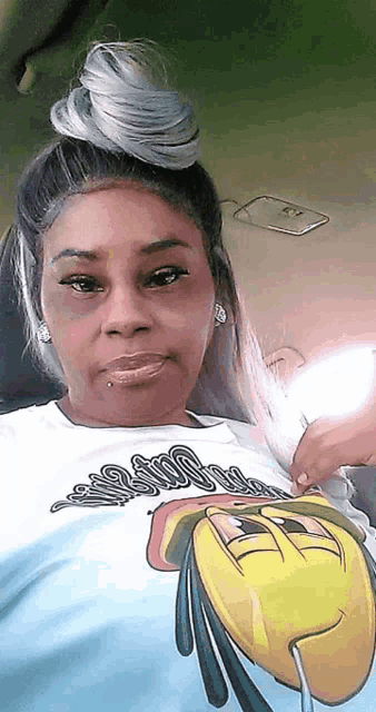 a woman is wearing a t-shirt with a cartoon face on it