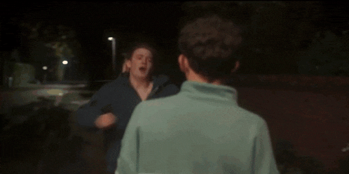 two men are hugging each other in a dark room .