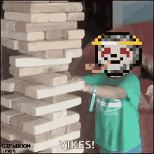 a kid playing jenga with a pixelated skull on his head
