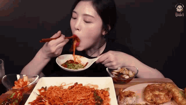 a woman is eating noodles with chopsticks and a spoon