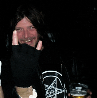 a man in a black shirt with a pentagram on it is holding a glass of beer