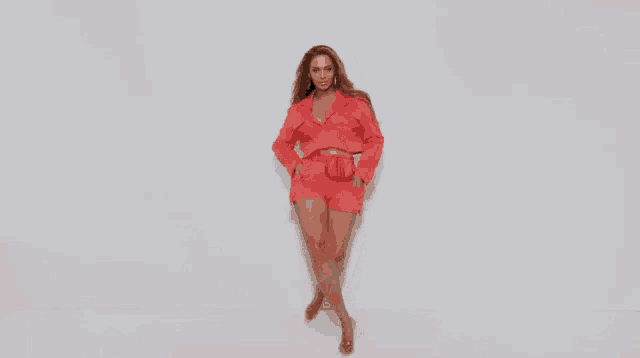 a woman in a red suit and shorts is standing in front of a white background .