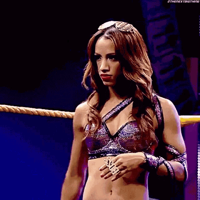a woman is standing in a wrestling ring wearing sunglasses and a bra .