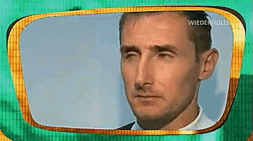 a man 's face is shown in a green and gold frame with the words wiederholu on the bottom right