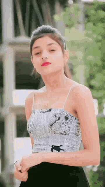 a young woman is wearing a newspaper top and a black skirt .