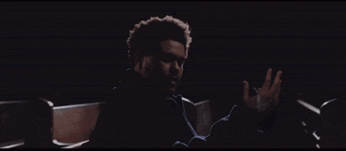 a man sitting in a dark room with his hand outstretched