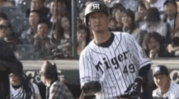 a baseball player is standing in front of a crowd while wearing a helmet .