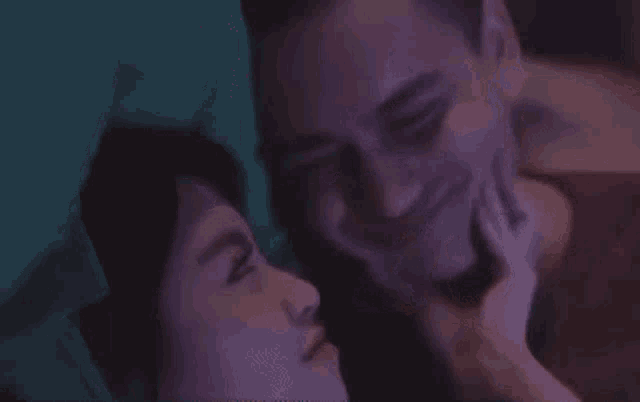 a man and a woman are kissing while laying on a bed .