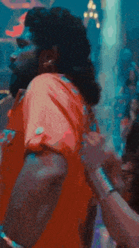 a man with a beard and long hair is dancing in a dark room .