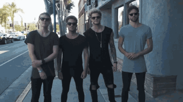 a group of young men are standing on a sidewalk in front of a building that says ' a & a ' on it