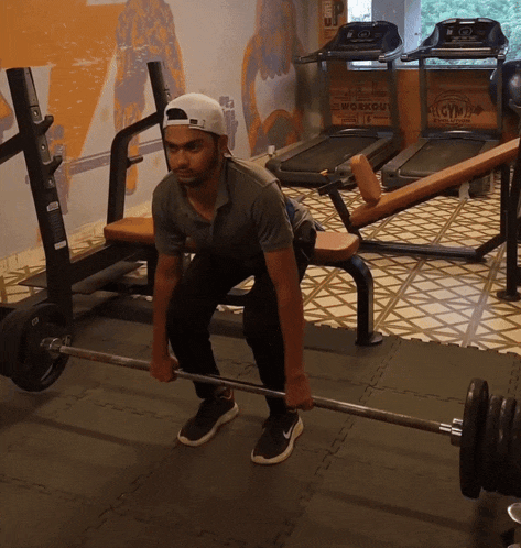 a man squatting down holding a barbell in a gym