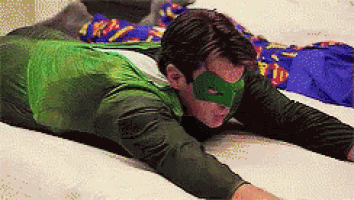 a man in a superhero costume is laying on a bed .