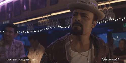 a man in a hat sits at a bar with a paramount logo on the bottom right