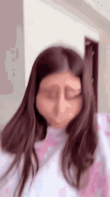 a woman with long brown hair is making a funny face .