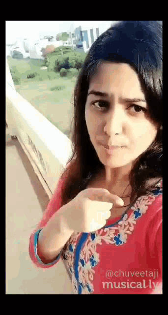 a woman in a pink and blue dress is taking a selfie .