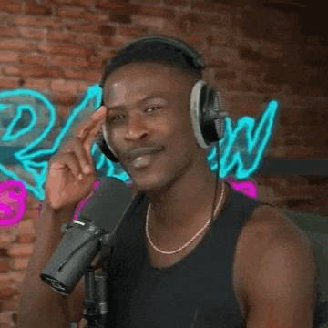 a man wearing headphones and a tank top is smiling in front of a microphone .