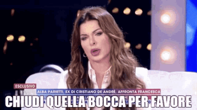 a woman with long hair is sitting on a couch with the words " chiudi quella bocca per favore " written below her