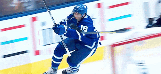 a hockey player with the number 16 on his jersey is flying through the air