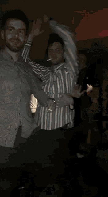 a man in a striped shirt is dancing in a crowd of people