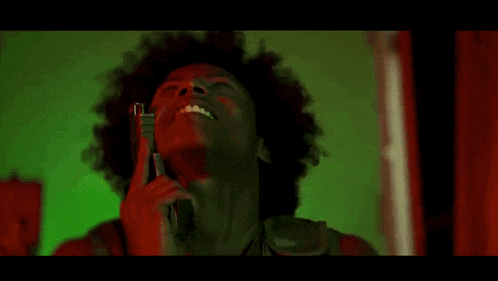 a man with an afro is shaving his face with a razor .