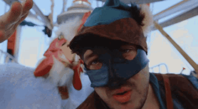 a man wearing a blue mask and a hat looks at the camera